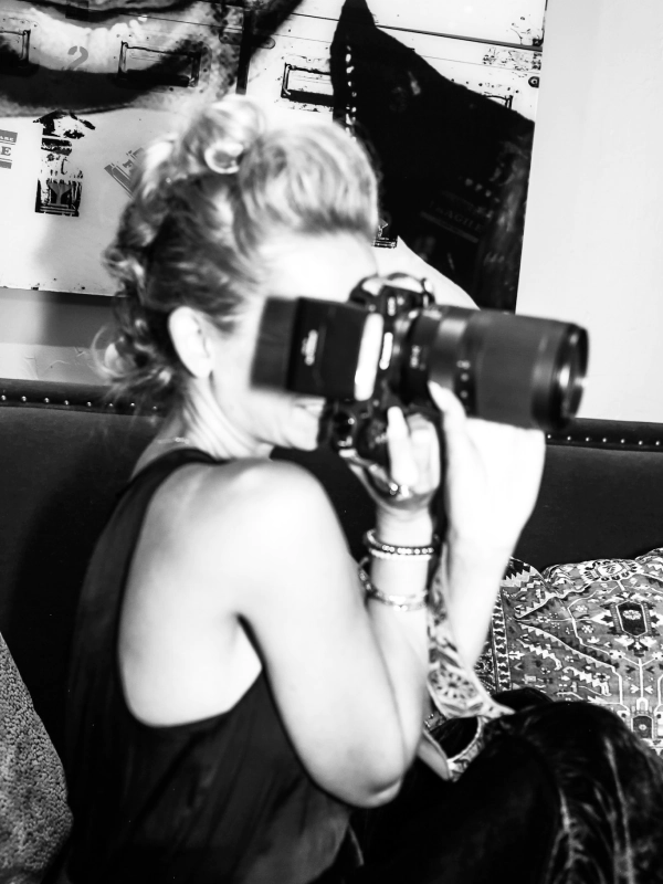 blonde woman holding a black camera taking a picture