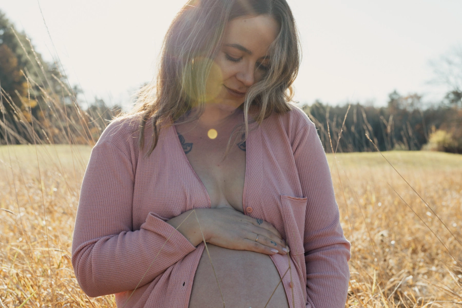 pregnant woman with a pink sweater on a field